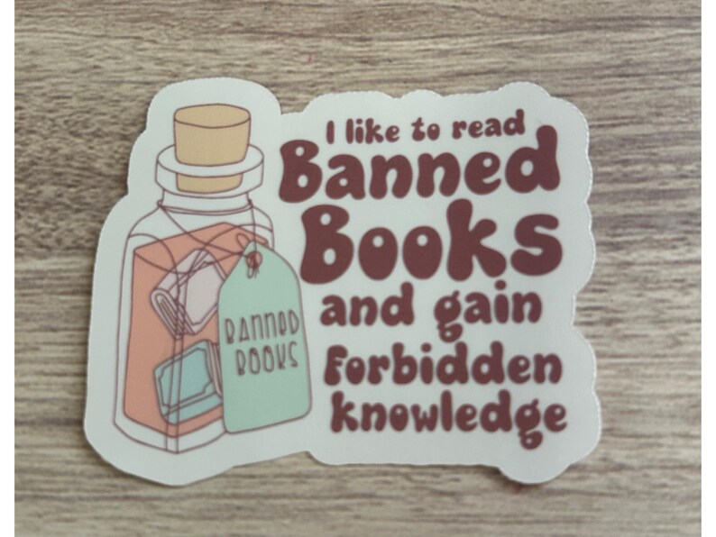 May include: A sticker with a jar illustration and the text "I like to read Banned Books and gain forbidden knowledge." The jar has a cork lid and a tag that says "Banned Books."