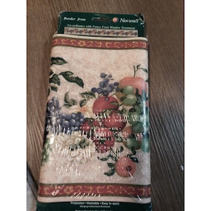 May include: A roll of wallpaper border featuring a fruit design with apples, grapes, and pomegranates in shades of red, purple, and green. The border is labeled "Norwall" and includes the text "Co-ordinates with Fancy Fruit Window Treatment."