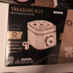 May include: A wooden treasure box with mechanical gears, featuring a custom password group and secret storage. The box is self-assembled and requires no glue. The box has a gear-shaped top and a dial on the side. The box is labeled LK502 and is made by ROKR.