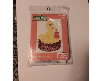 May include: A Sesame Street Friends needlecraft kit featuring Big Bird. The kit includes a design of Big Bird in a nest, holding a bag of seeds. The finished size is 5" x 7". The kit is packaged in a clear plastic bag.