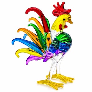 May include: A multi-colored glass rooster figurine featuring a vibrant red comb, a yellow head, and a body transitioning through green, blue, and purple hues. The tail consists of long, curved glass feathers in red, orange, green, blue, and purple.