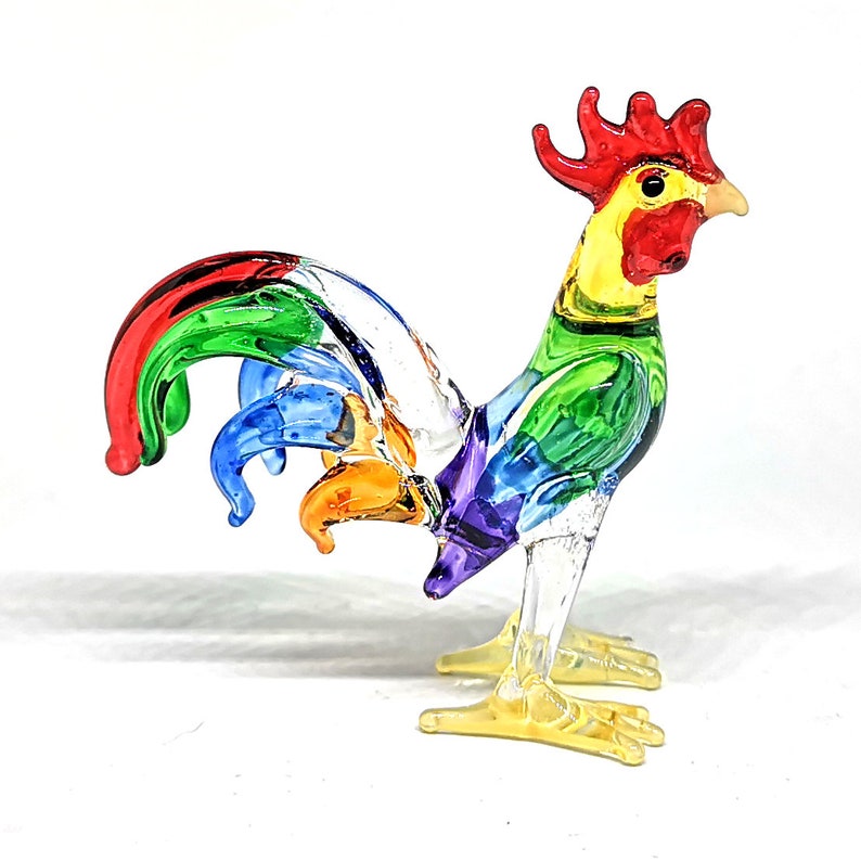 May include: A colorful glass rooster figurine with a red comb, yellow beak, and a rainbow-colored tail.