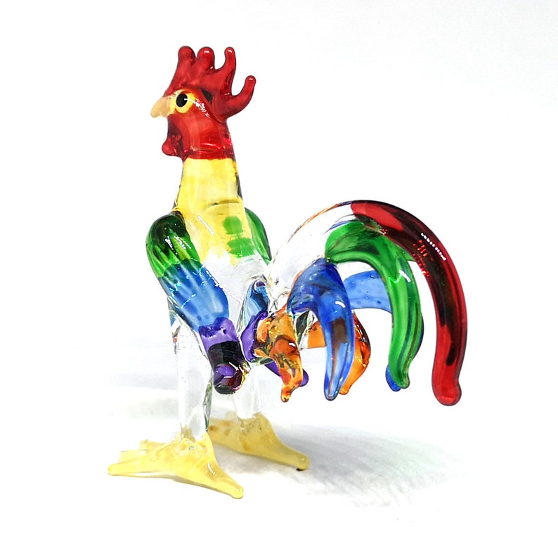 May include: A colorful glass rooster figurine with a red comb, yellow beak, and a tail with green, blue, and red feathers.