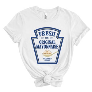 May include: White t-shirt with a blue and white graphic of a mayonnaise jar label that says "FRESH EST? 1857 EST? ORIGINAL MAYONNAISE 100% CAGE FREE EGGS DELICIOUSLY CREAMY"