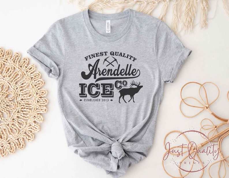 Puede incluir: Camiseta gris con texto negro que dice "Finest Quality Arendelle Ice Co. Established 2013" y una silueta negra de un ciervo.