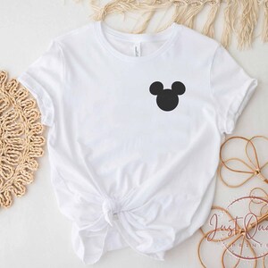 K&ouml;nnte beinhalten: Wei&szlig;es T-Shirt mit einer schwarzen Mickey Mouse Silhouette auf der Vorderseite.