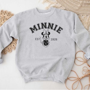 May include: Gray sweatshirt with a black and white graphic of Minnie Mouse and the text "MINNIE EST 1928".