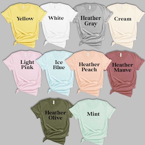 May include: A collection of ten unisex t-shirts in various colors, including yellow, white, heather gray, cream, light pink, ice blue, heather peach, heather mauve, heather olive, and mint. Each t-shirt has a different color and a text label indicating the color.