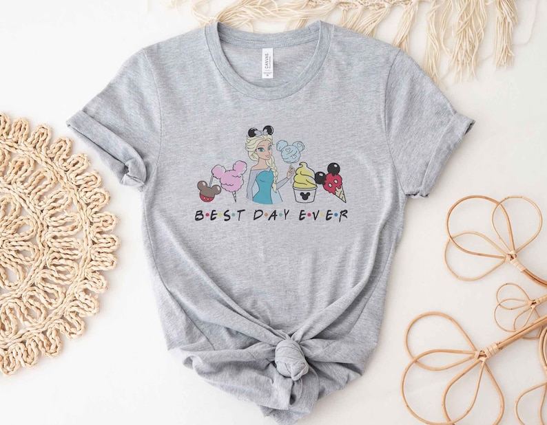 May include: Gray t-shirt with a graphic of a cartoon Disney princess holding a Mickey Mouse ice cream cone. The text "BEST DAY EVER" is printed below the graphic.