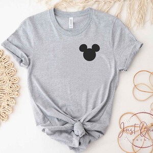 K&ouml;nnte beinhalten: Ein graues T-Shirt mit einer schwarzen Mickey Mouse-Silhouette auf der Vorderseite.