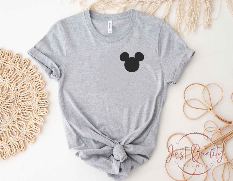 K&ouml;nnte beinhalten: Ein graues T-Shirt mit einer schwarzen Mickey Mouse-Silhouette auf der Vorderseite.