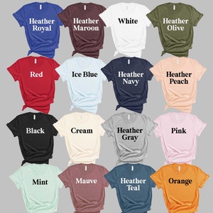 K&ouml;nnte beinhalten: Eine Auswahl von 16 Unisex-T-Shirt-Farben, darunter Heather Royal, Heather Maroon, Wei&szlig;, Heather Olive, Rot, Eisblau, Heather Navy, Heather Peach, Schwarz, Creme, Heather Grey, Pink, Mint, Mauve, Heather Teal und Orange.
