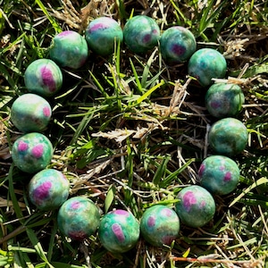 May include: A white ceramic mug with a black handle and the text "But First, Coffee" in a black, handwritten-style font. The mug is on a white surface.