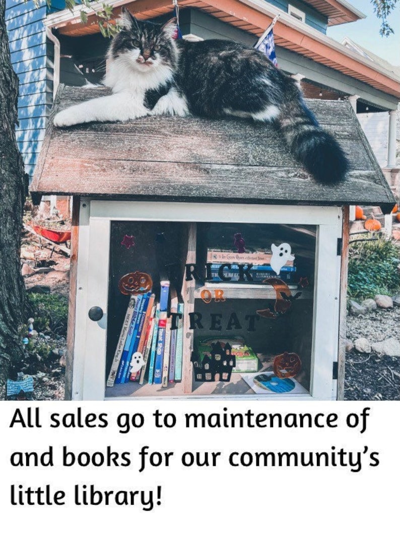 May include: A small wooden library with a glass door, decorated with Halloween-themed stickers, including a ghost, a pumpkin, and a witch's hat. The library is filled with books and a CD. A black and white cat sits on the roof of the library. The text "Trick or Treat" is visible on the door.