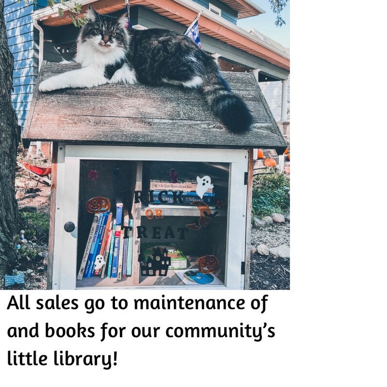 May include: A small wooden library with a cat sitting on the roof. The library has a glass door with a sign that says "Trick or Treat" and is filled with books. The sign below the library says "All sales go to maintenance of and books for our community's little library!"
