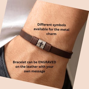 May include: A brown leather bracelet with a silver-colored cross charm. The bracelet is shown on a wrist. Text on the image says, "Different symbols available for the metal charm" and "Bracelet can be ENGRAVED on the leather with your own message."