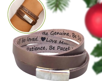 Puede incluir: Una pulsera envolvente de cuero marrón con un cierre plateado. La pulsera está grabada con las palabras "Be loved. Be Genuine, Be Strong, Love More, Patience, Be Peaceful." La pulsera se muestra en una muñeca en una imagen más pequeña.