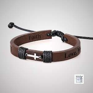 May include: A brown leather bracelet featuring a silver-toned cross charm flanked by black cord wrappings. The leather band is engraved with the word Faith and the text Love, Me. It includes adjustable black cord ties at the ends.