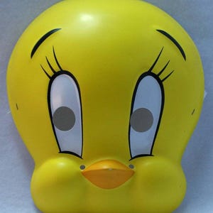Puede incluir: Una máscara amarilla de Pío Pío con pestañas y cejas negras, ojos blancos y un pico naranja. La máscara de cara completa está diseñada para disfraces o cosplay.