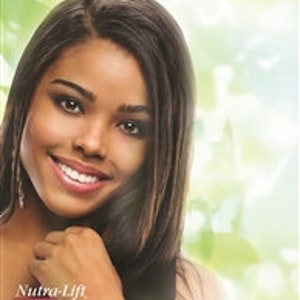 May include: A smiling woman with long, dark hair and fair skin. She is wearing a white top. The image has a soft focus background with green and white tones. The text "Nutra-Lift" is visible in the lower left corner.