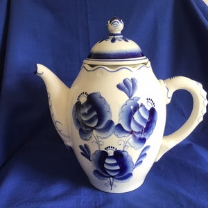 May include: A white ceramic teapot with a blue and white floral design. The teapot has a lid and a handle.