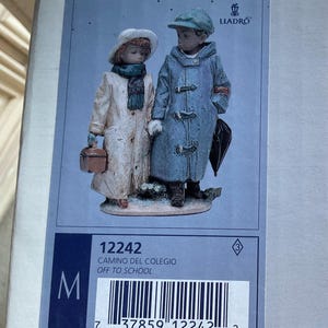 May include: A porcelain figurine of two children in winter coats, one holding a lunchbox and the other an umbrella. The figurine is labeled "LLADRÓ" and "OFF TO SCHOOL". The base has the number "12242".