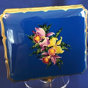 May include: A vintage blue enamel cigarette case with a gold trim and a floral design featuring pink, yellow, and red flowers.