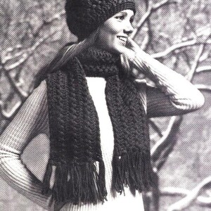 May include: A black crocheted hat with a pompom on top and a matching black crocheted scarf with fringe. The hat and scarf are worn by a person in a white sweater and jeans. The text "YOUTHFUL LOOK NOW IS THE TIME" is visible in the image.