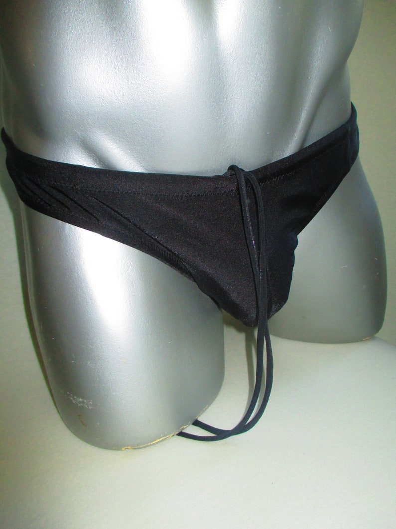 May include: Black swim briefs with a drawstring tie. The briefs are made of a smooth, silky fabric.