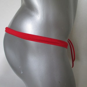 Op de afbeelding: Rood string bikini broekje met verstelbare bandjes. Het bikini broekje is gemaakt van een zachte, rekbare stof.