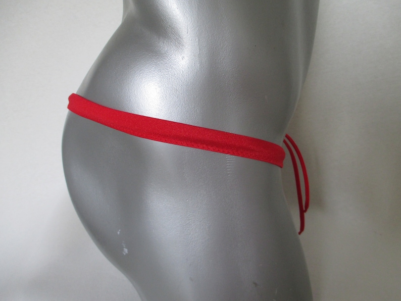 Op de afbeelding: Rood string bikini broekje met verstelbare bandjes. Het bikini broekje is gemaakt van een zachte, rekbare stof.