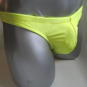 May include: A bright yellow swimsuit with a low rise cut. The swimsuit is made of a smooth, shiny fabric.
