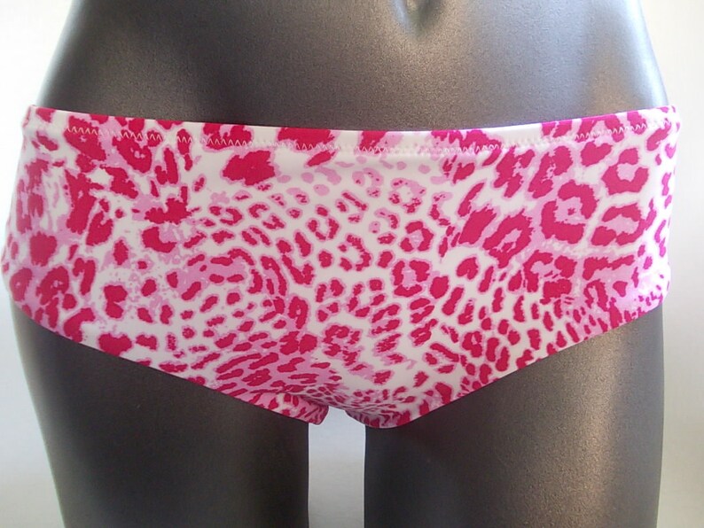 May include: Pink and white leopard print bikini bottom. The fabric has a soft, stretchy feel.