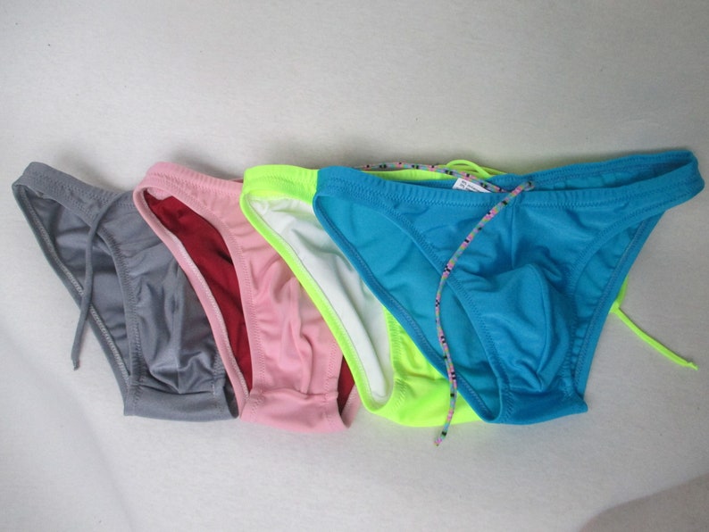 May include: Five pairs of men's swim briefs in different colors: gray, burgundy, pink, neon green, and turquoise. Each pair has a drawstring.
