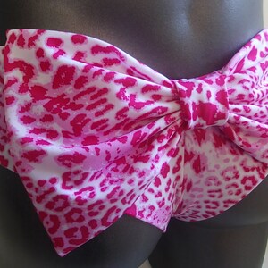 May include: Pink and white leopard print bikini bottom with a large bow in the back.