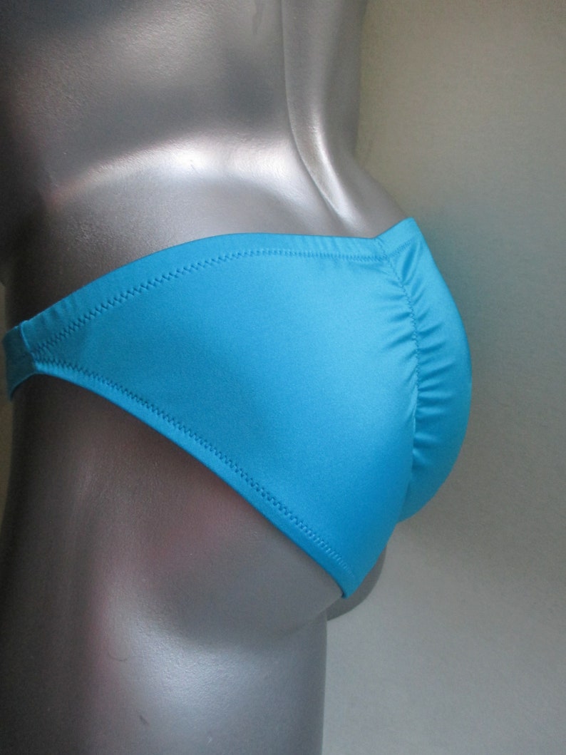 May include: A turquoise blue swimsuit with a low-cut back and a cheeky cut in the front.