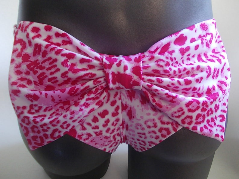 May include: Pink and white leopard print bikini bottoms with a large bow in the back.