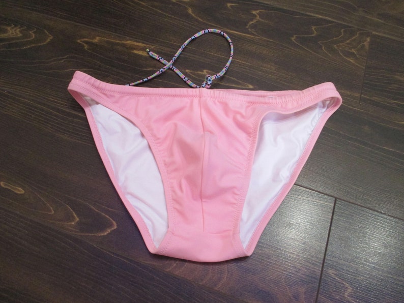 May include: Pink swim briefs with a white lining and a patterned drawstring.