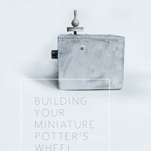 Op de afbeelding: Een klein, grijs, metalen pottenbakkerswiel met een witte kleivase erop. De tekst "BUILDING YOUR MINIATURE POTTER'S WHEEL" staat onder het wiel.