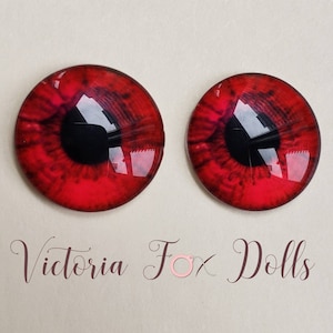 Può includere: Coppia di occhi di bambola in vetro rosso con pupille nere. Gli occhi hanno un design dettagliato con vortici rossi e neri.