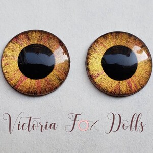 Puede incluir: Dos ojos de vidrio marrón dorado con pupilas negras y un diseño de purpurina roja y dorada. Los ojos son para hacer muñecas.