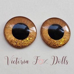 Puede incluir: Dos ojos de muñeca redondos de color marrón y dorado con purpurina y pupilas negras. Los ojos tienen un acabado brillante.