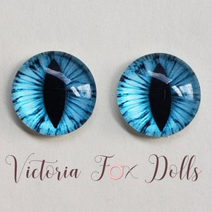 May include: Two blue glass eyes with black pupils, designed for doll making. The eyes have a realistic cat eye design.
