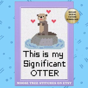 Könnte beinhalten: Ein Kreuzstichmuster mit einer Cartoon-Otter, die auf einem Felsen im Wasser sitzt, mit Herzen, die um sie herum schweben. Der Text darunter lautet "This is my Significant OTTER".
