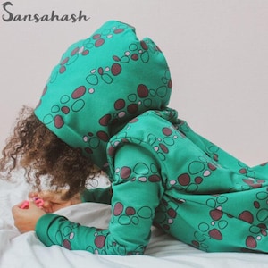 Op de afbeelding: Een groene hoodie met een patroon van bruine en grijze cirkels. De hoodie is gemaakt van zachte, comfortabele stof en heeft een ontspannen pasvorm.