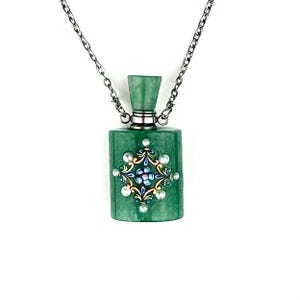 Op de afbeelding: Een groene rechthoekige hangerketting met een zilveren ketting. De hanger heeft de vorm van een fles met een decoratief bloemmotief in het midden, met blauwe, gouden en witte accenten. De fles heeft een zilveren dop.