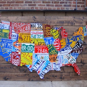 May include: A wooden wall art piece shaped like the United States of America, made from license plates from each state. The license plates are arranged to form the outline of the country.