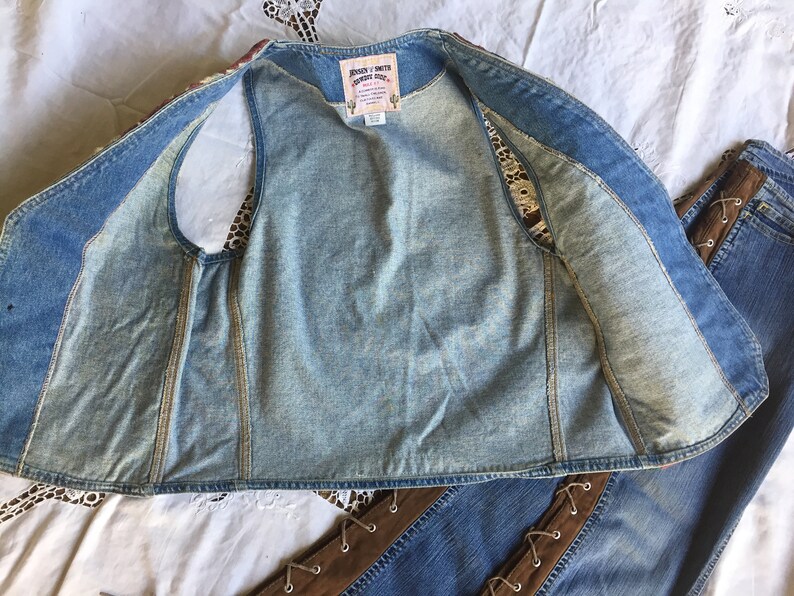K&ouml;nnte beinhalten: Eine Jeansweste mit einem braunen und wei&szlig;en Blumenmuster auf der R&uuml;ckseite. Die Weste ist offen und das Innere ist sichtbar. Die Weste hat ein Etikett mit der Aufschrift "Johnny & Smith Country Style".