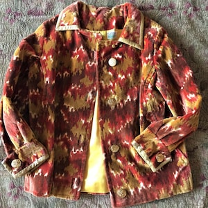 May include: A red, brown, and white patterned velvet jacket with gold buttons and a yellow lining. The jacket has a collar and long sleeves.