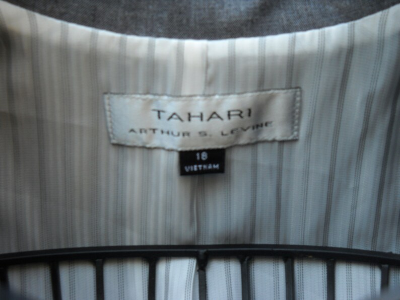 May include: A white label with the text "TAHARI ARTHUR S. LEVINE" and a smaller label with the text "16 VIETNAM" on a striped fabric background.